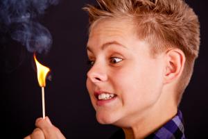 Boy holding burning matchstick